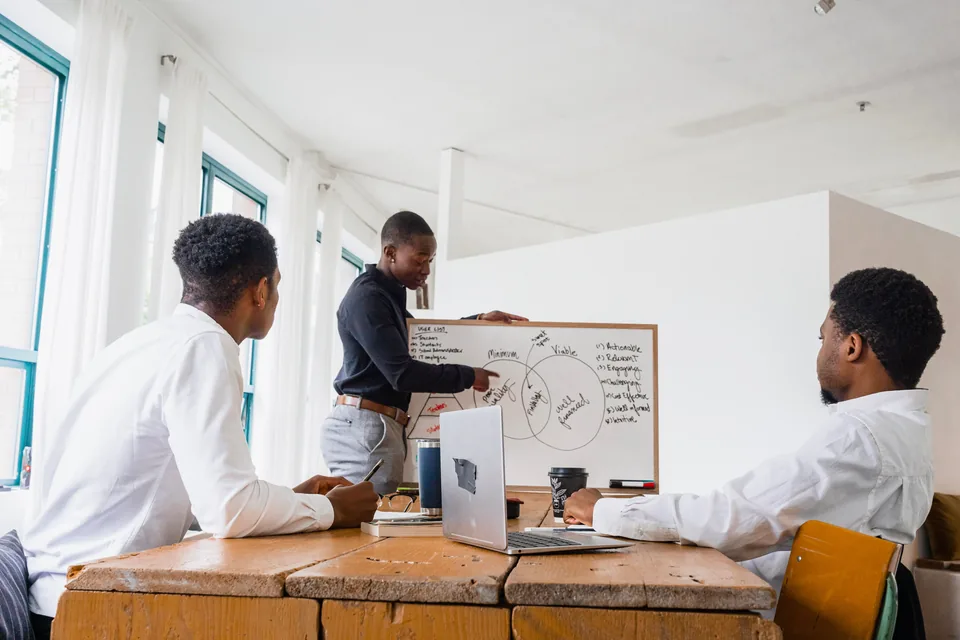 A team plans a project around a whiteboard.